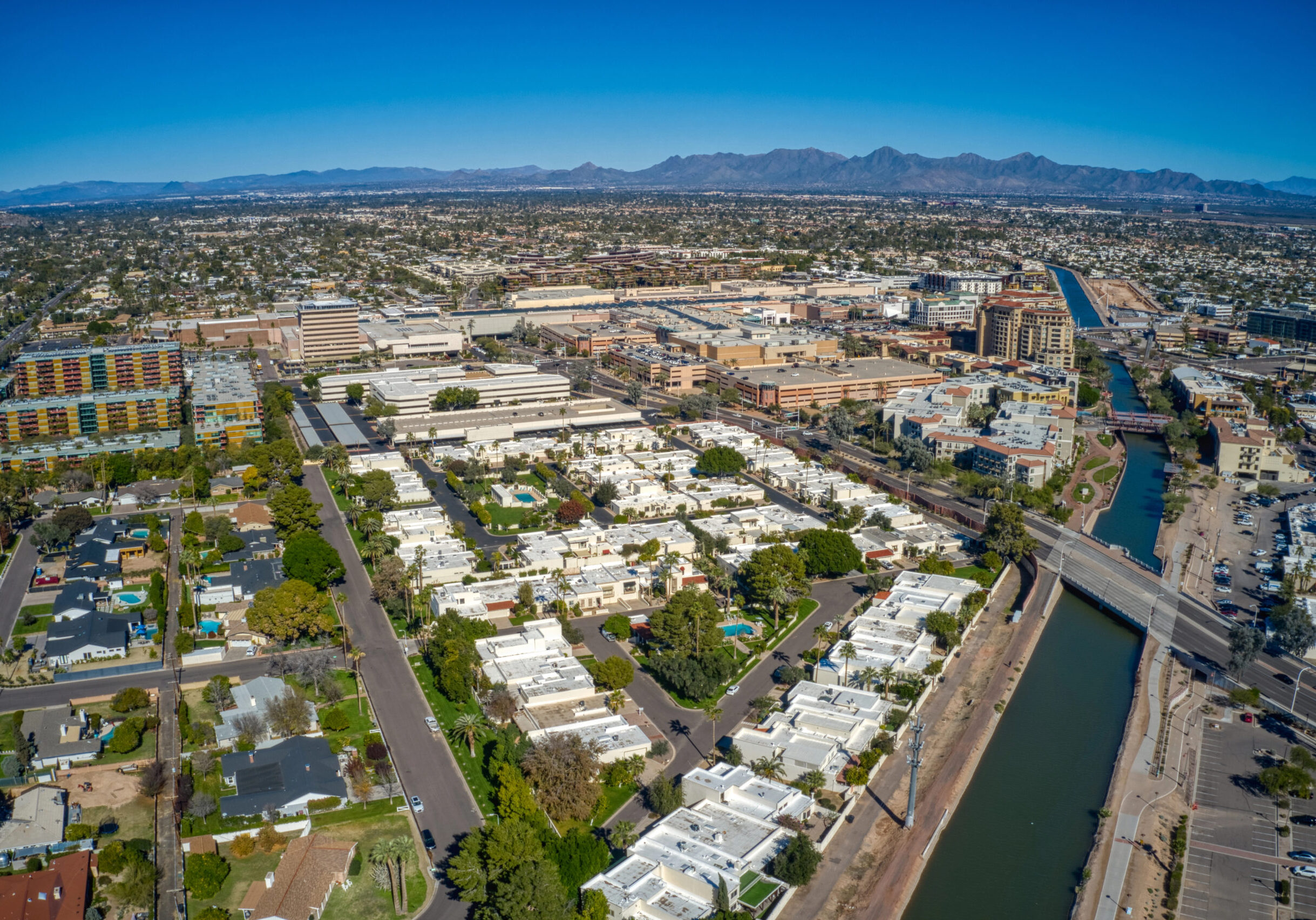 Scottsdale Aerial view of Scottsdale, Arizona, showcasing residential and commercial properties, with a focus on white-roofed homes, greenery, and nearby waterways, reflecting the local environment and community.